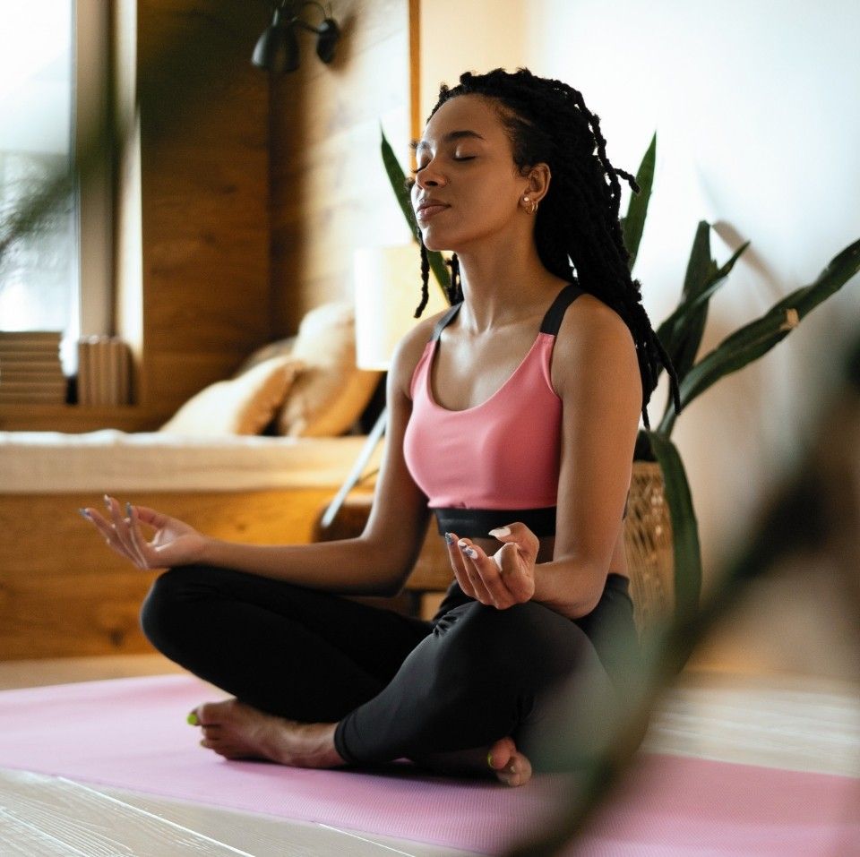 Person meditating on a yoga mat at home