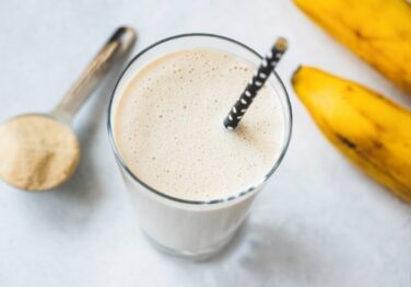 Glass of protein smoothie with banana and protein powder